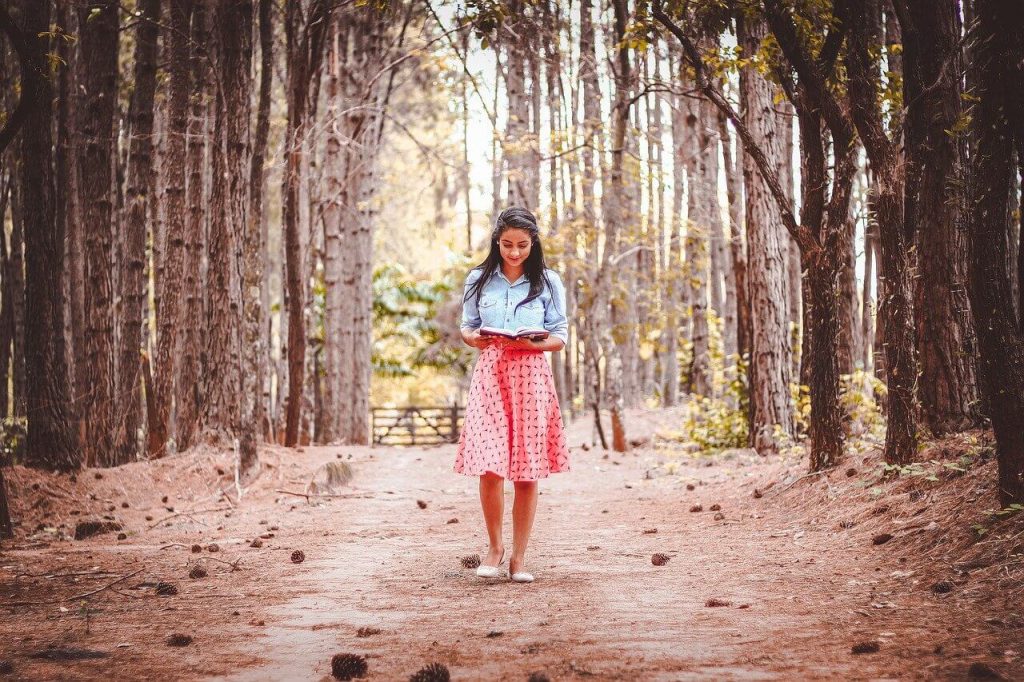 책을 읽으면 숲 속 산책길 걷는 여자
